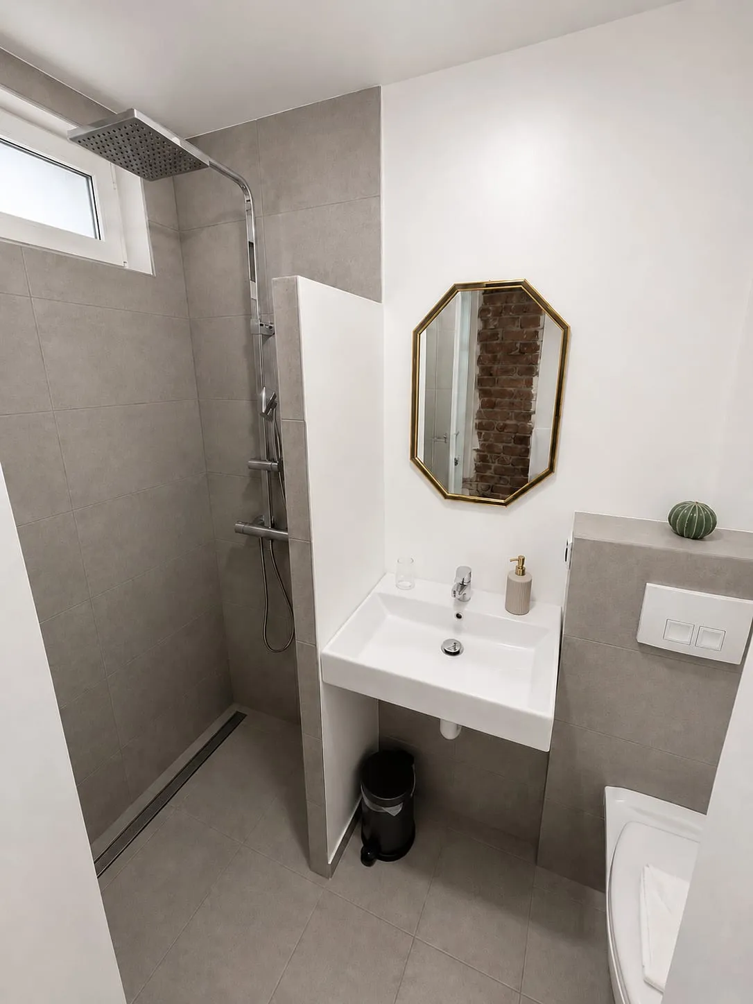Badezimmer mit begehbarer Dusche und achteckigem Spiegel