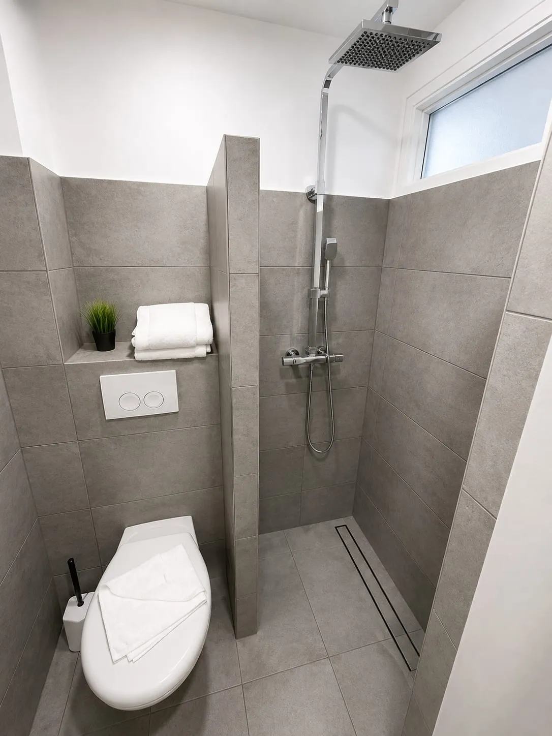 Badezimmer mit begehbarer Regendusche und grauen Fliesen