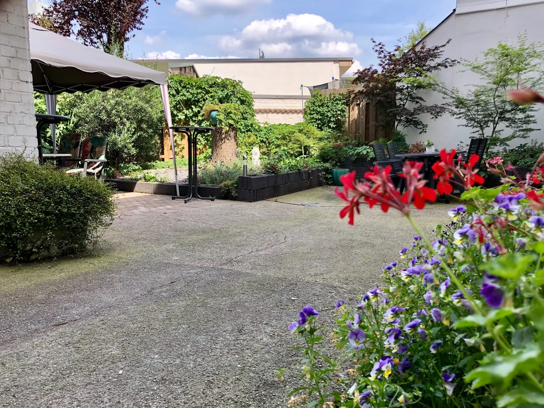 Innenhof mit Blumen im Vordergrund an einem sonnigen Tag