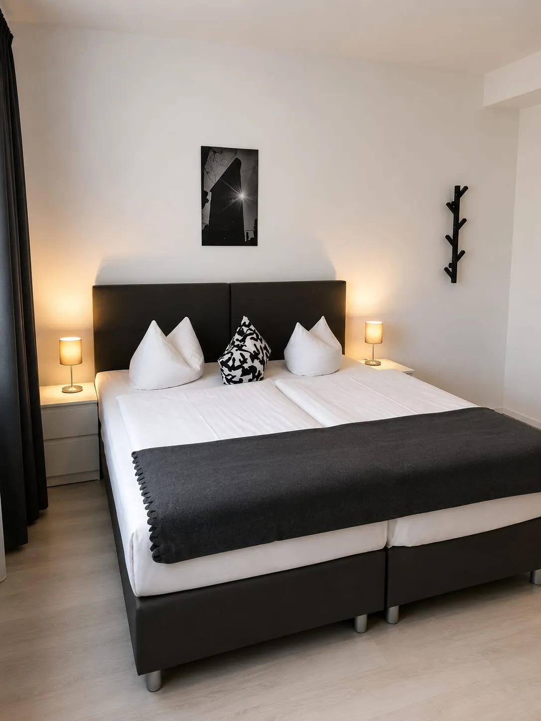 Doppelzimmer mit dunklem Bettkopfteil und Nachttischlampen
