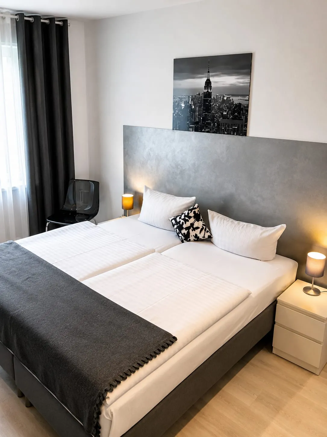 Doppelzimmer mit zwei zusammengestellten Betten vor grauer Wand