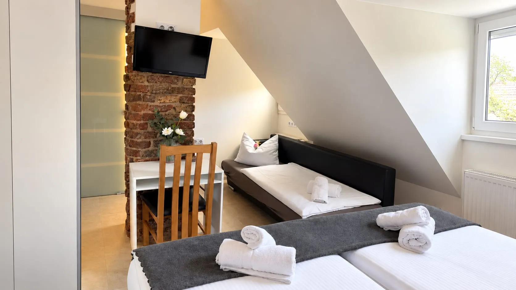 Familienzimmer mit Schlafcouch, Schreibtisch und Ziegelsäule