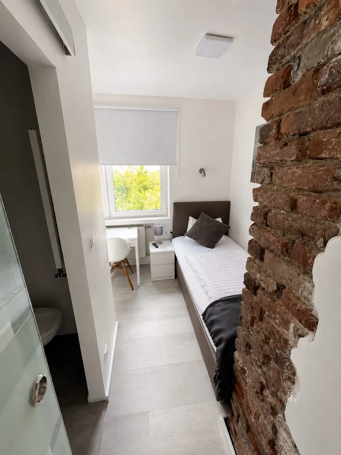 Schmales Einzelzimmer mit Schreibtisch am Fenster
